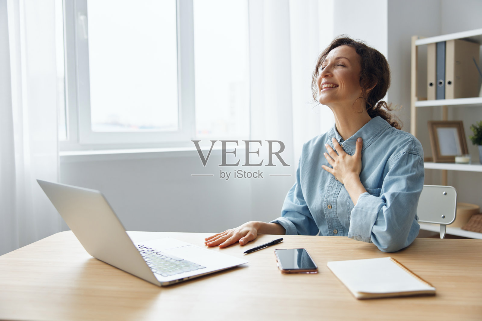 快乐热情快乐满足可爱的女上班族自由职业者得到期待已久的积极的工作回应和赞扬她的工作，抱臂在胸前，微笑。是的，我把它变成了概念照片摄影图片