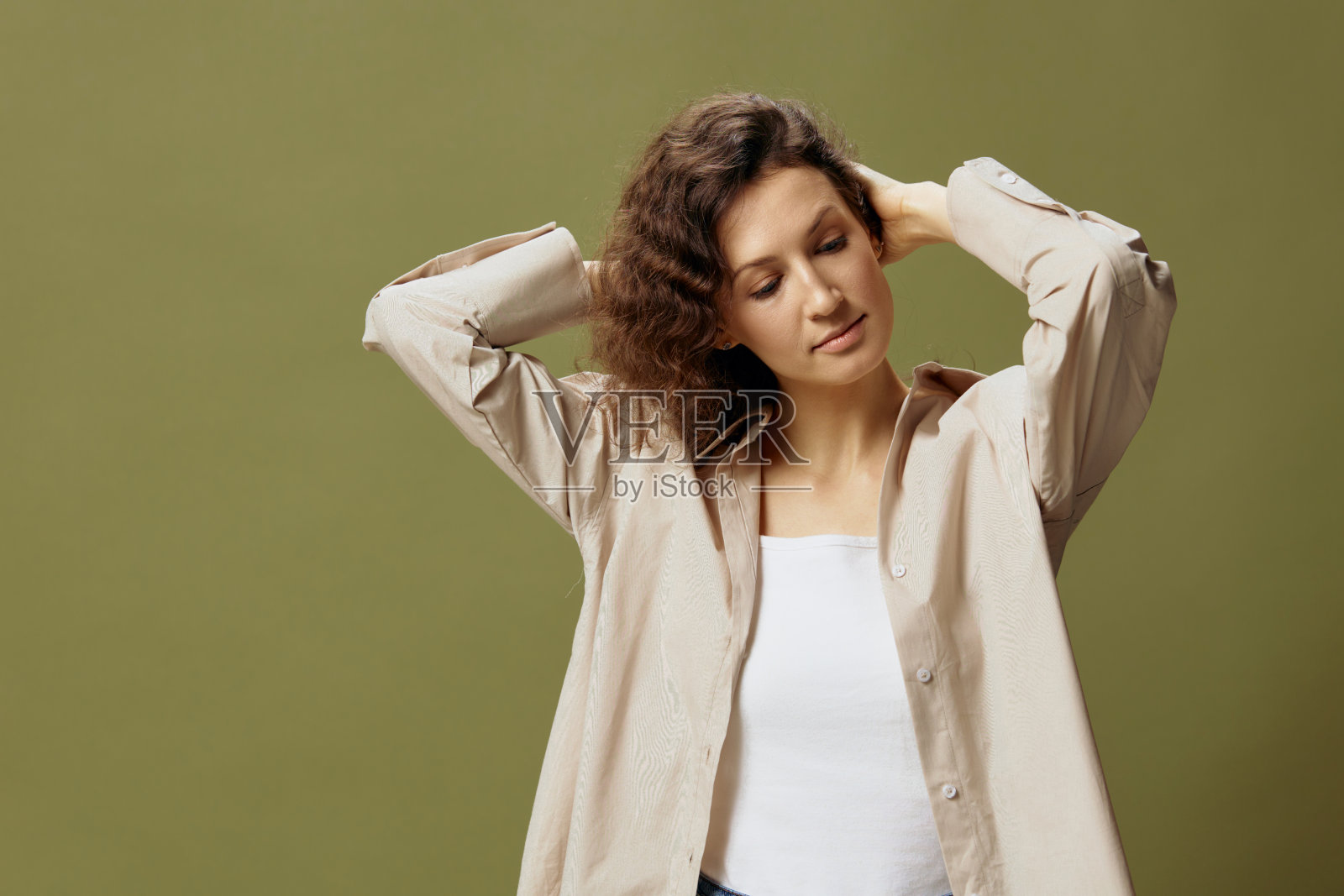 可爱的开朗快乐的卷曲美丽的女性在亚麻休闲衬衫触摸头发看起来一边摆出孤立的橄榄绿柔和的背景。人，生活方式，情感。本空间照片摄影图片