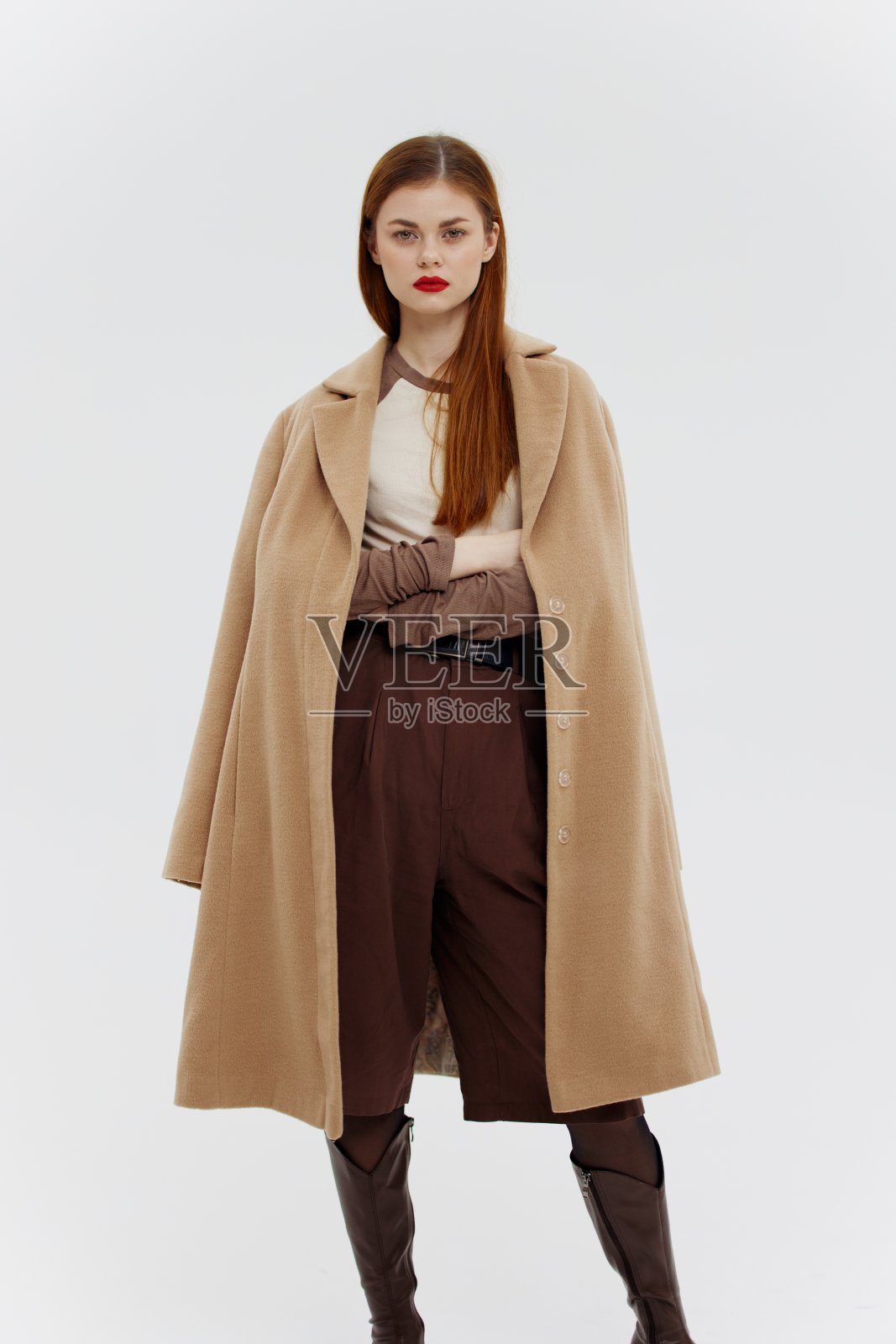 拍摄外衣目录。在白色背景下的工作室里，红发美女身穿米色长裙照片摄影图片