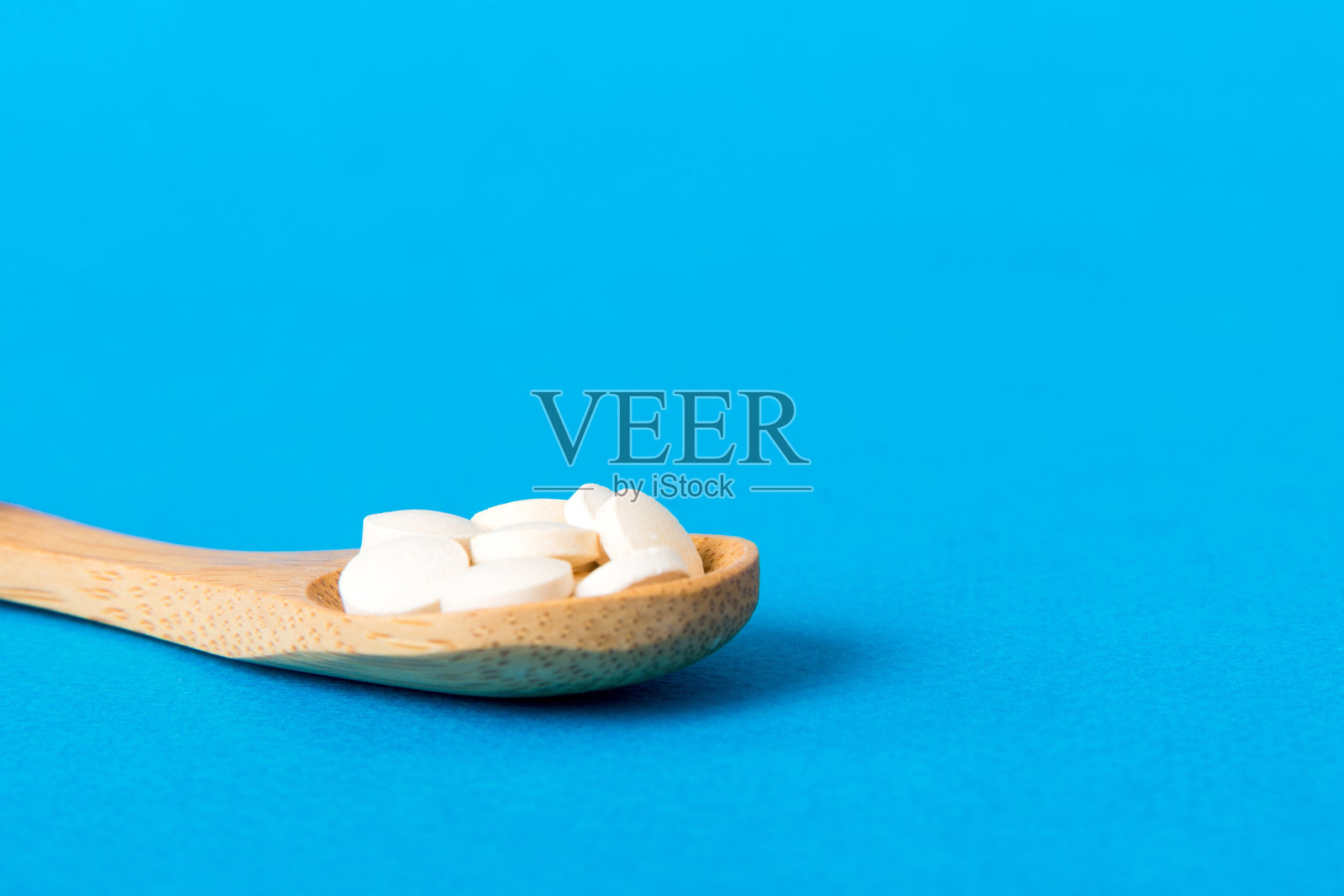 彩色背景上的一堆白色药片。桌子上散落着药片。成堆的红色软明胶胶囊。维生素和膳食补充剂的概念照片摄影图片