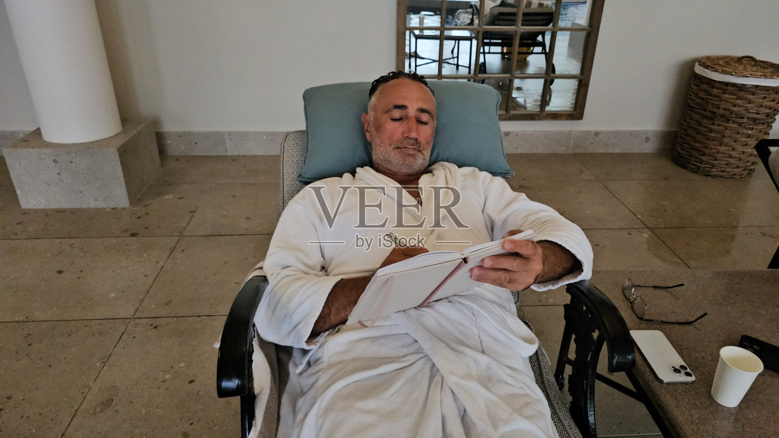 一位老人躺在躺椅上写笔记，正在一家放松水疗中心休息照片摄影图片