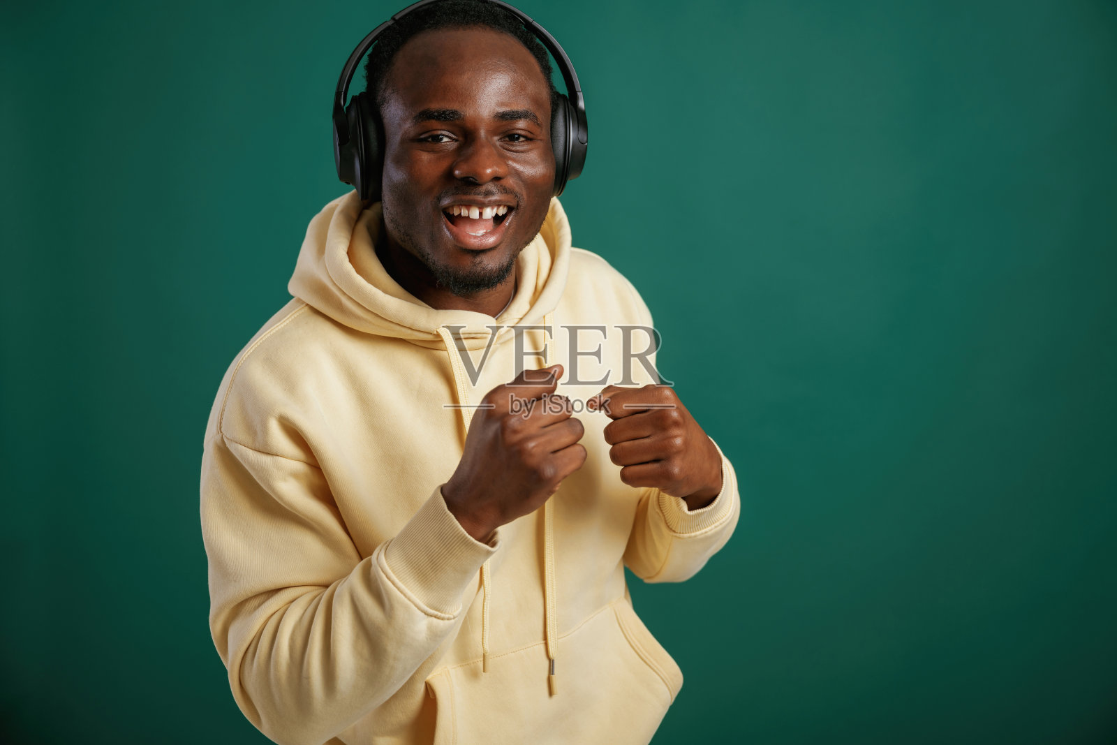 听着音乐，跳舞。一个非洲裔美国人站在演播室的绿色背景下照片摄影图片