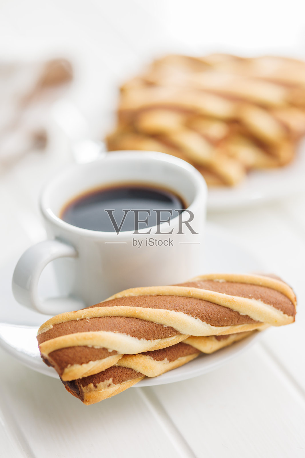 白色桌子上的经典条纹饼干和咖啡杯。照片摄影图片