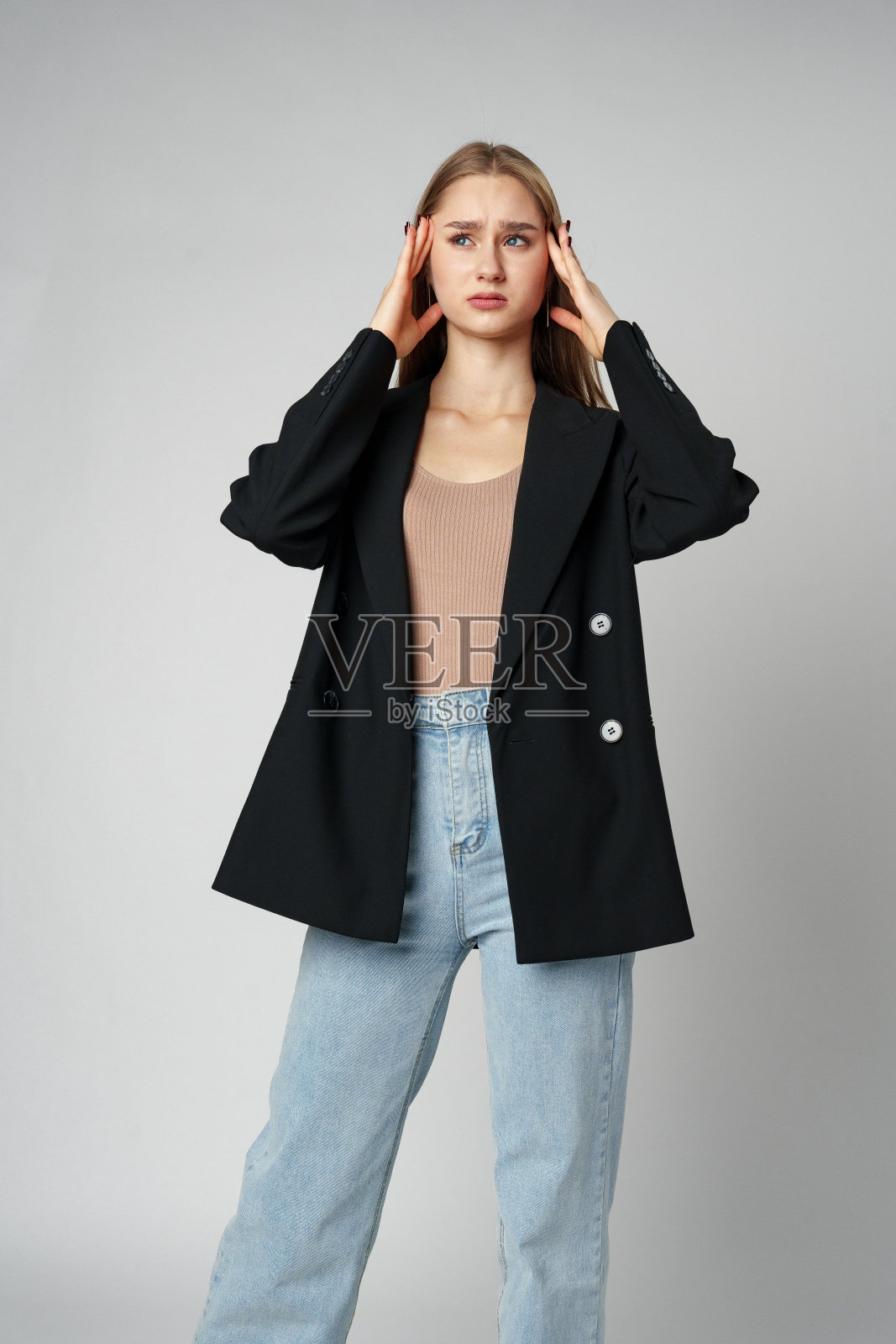 在灰色背景下，女人用手捂脸摆姿势照片摄影图片