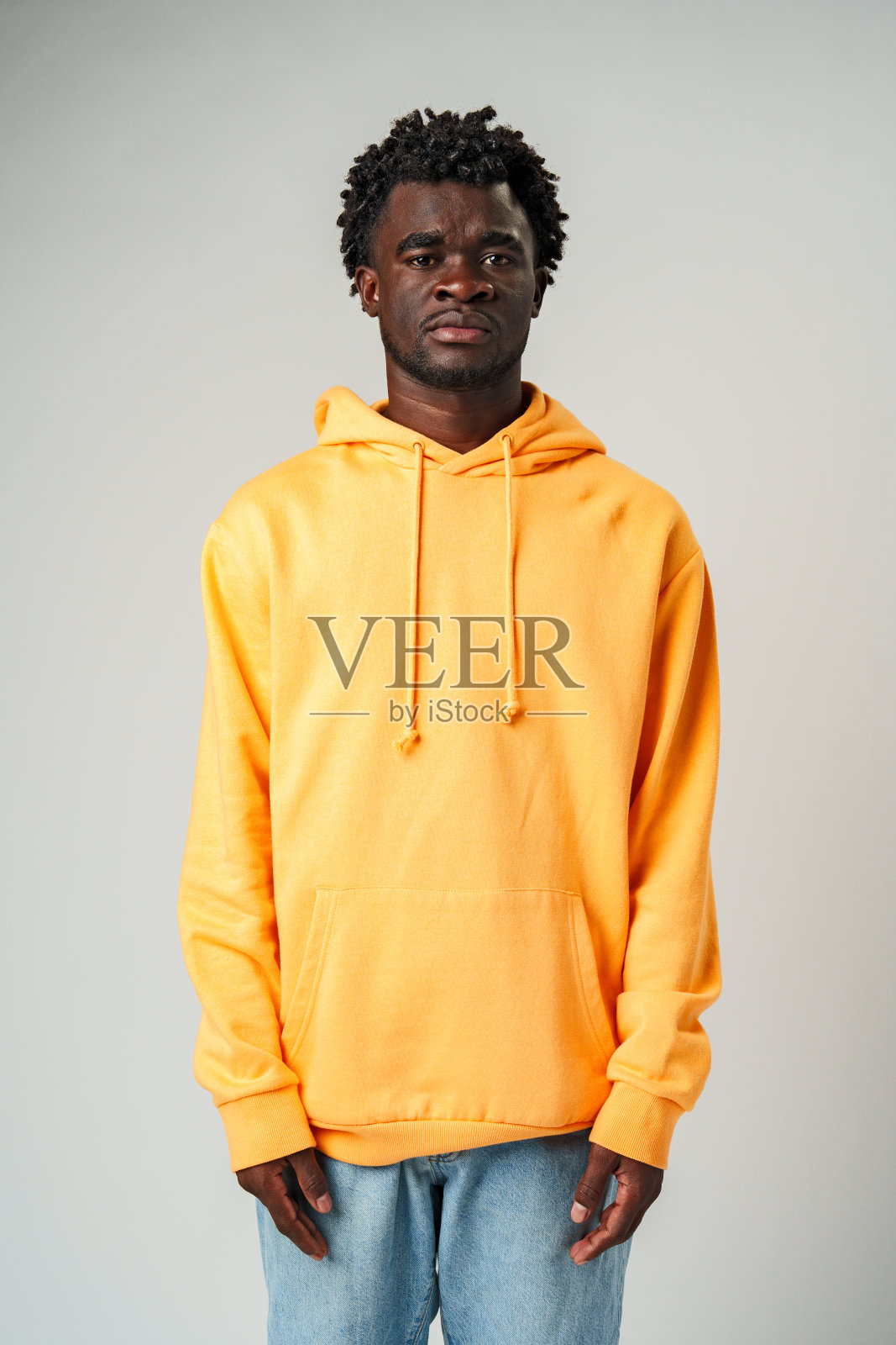 身穿黄色连帽衫的非洲人站在灰墙前照片摄影图片