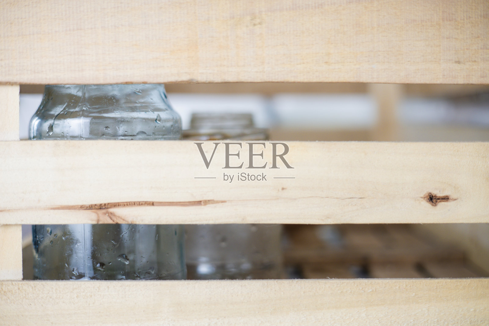 厨房里有一个需要回收利用的装有玻璃的木箱。将玻璃废料收集到一个盒子里进行回收。厨房里的一位家庭主妇正在收集旧玻璃瓶，准备回收利用。照片摄影图片