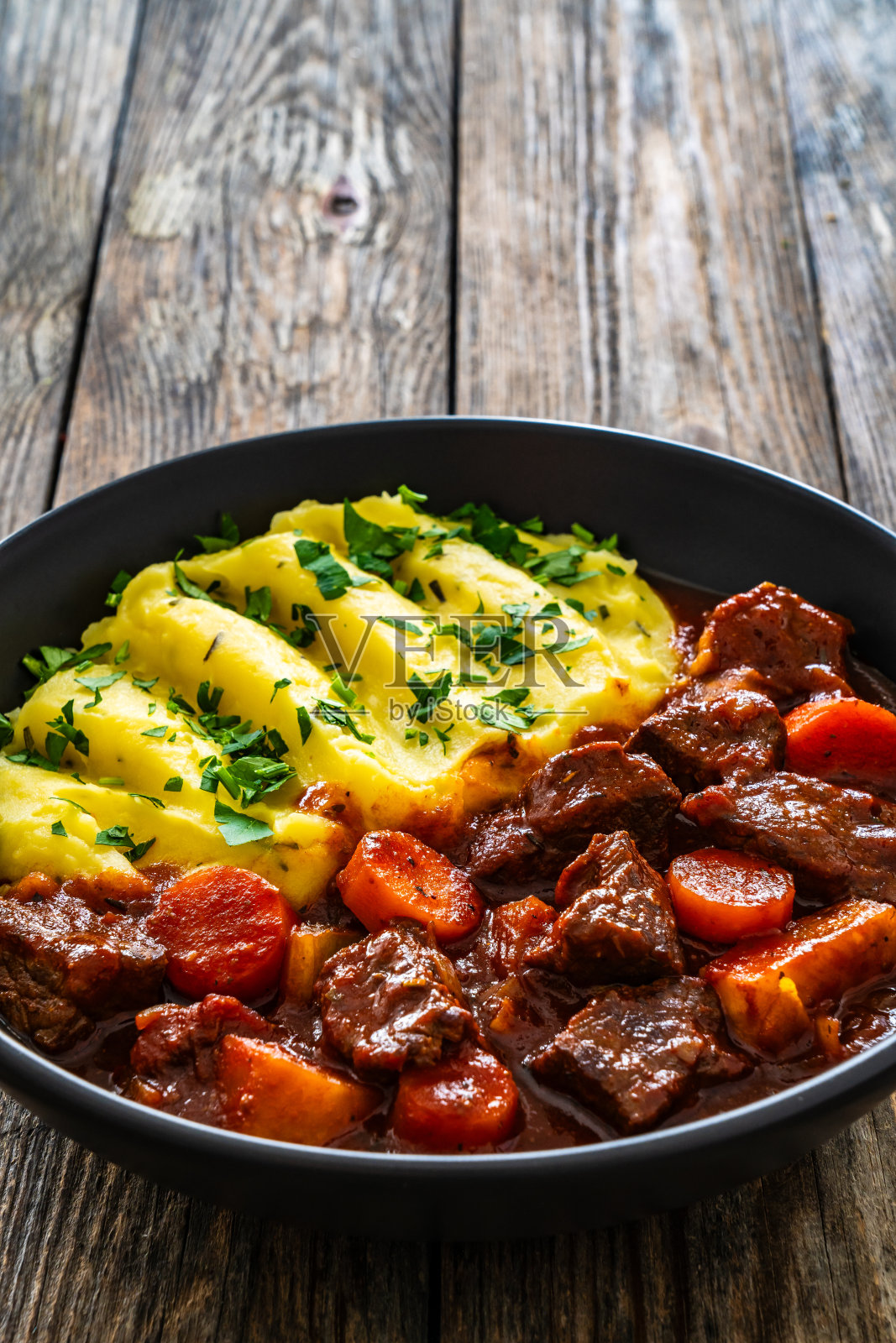 圣帕特里克节的爱尔兰炖菜——啤酒烤牛肉和土豆泥放在木桌上照片摄影图片