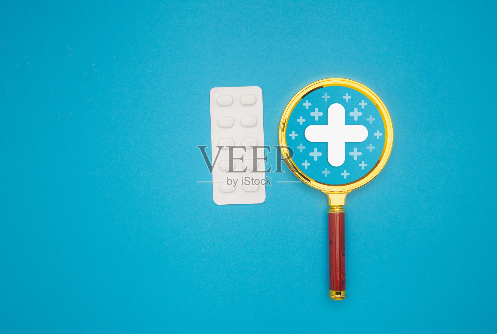 蓝色背景上的医用放大镜和药片。照片摄影图片