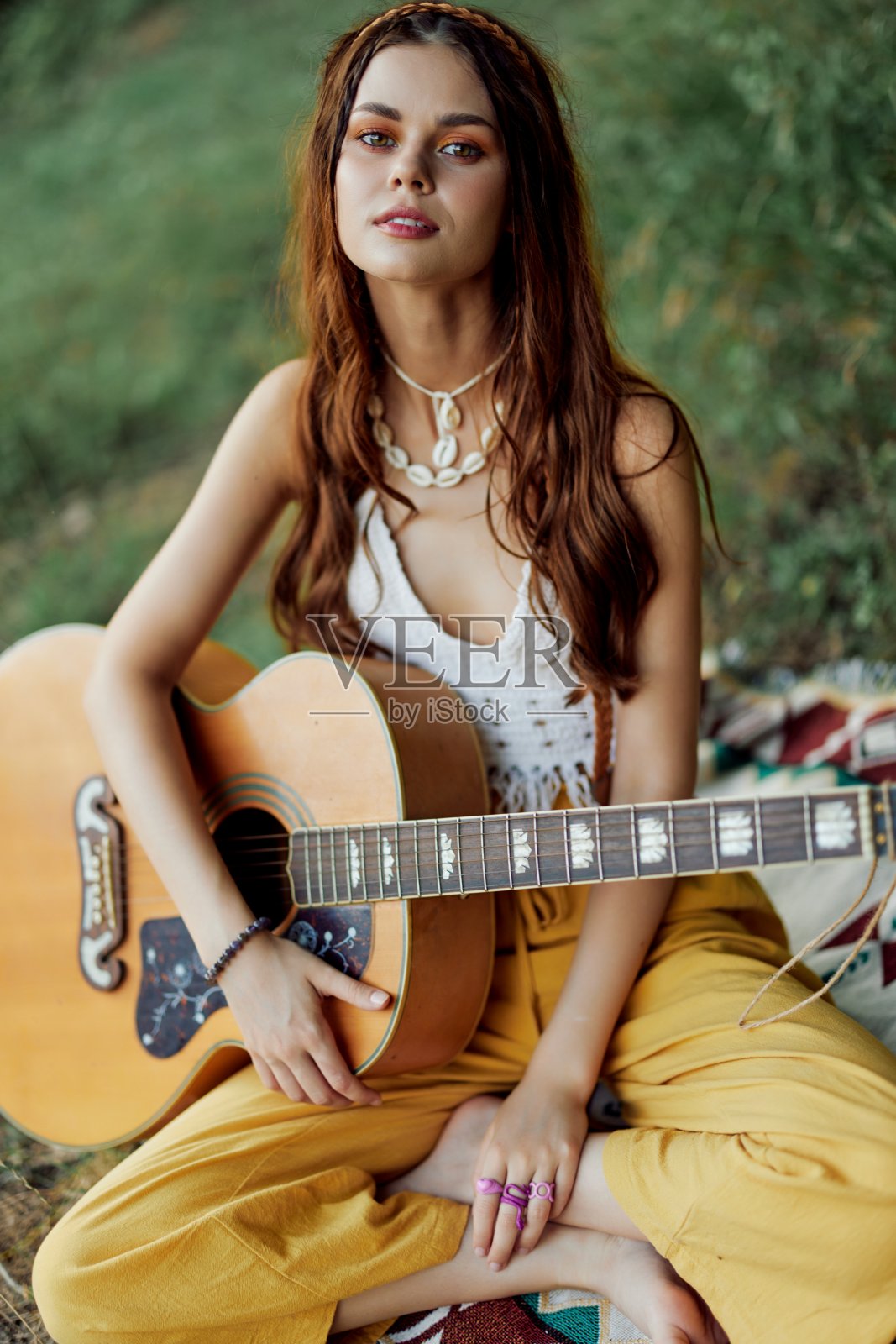 快乐的嬉皮女人带着吉他坐在湖边的大自然中微笑照片摄影图片