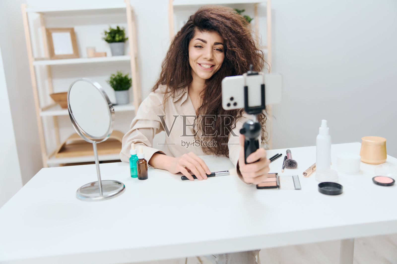 开朗友好的晒黑英俊卷曲的拉丁美女博主亚麻衬衫与远方的朋友在家里说话。复制空间模拟横幅。网红用智能手机录制视频评论博客照片摄影图片