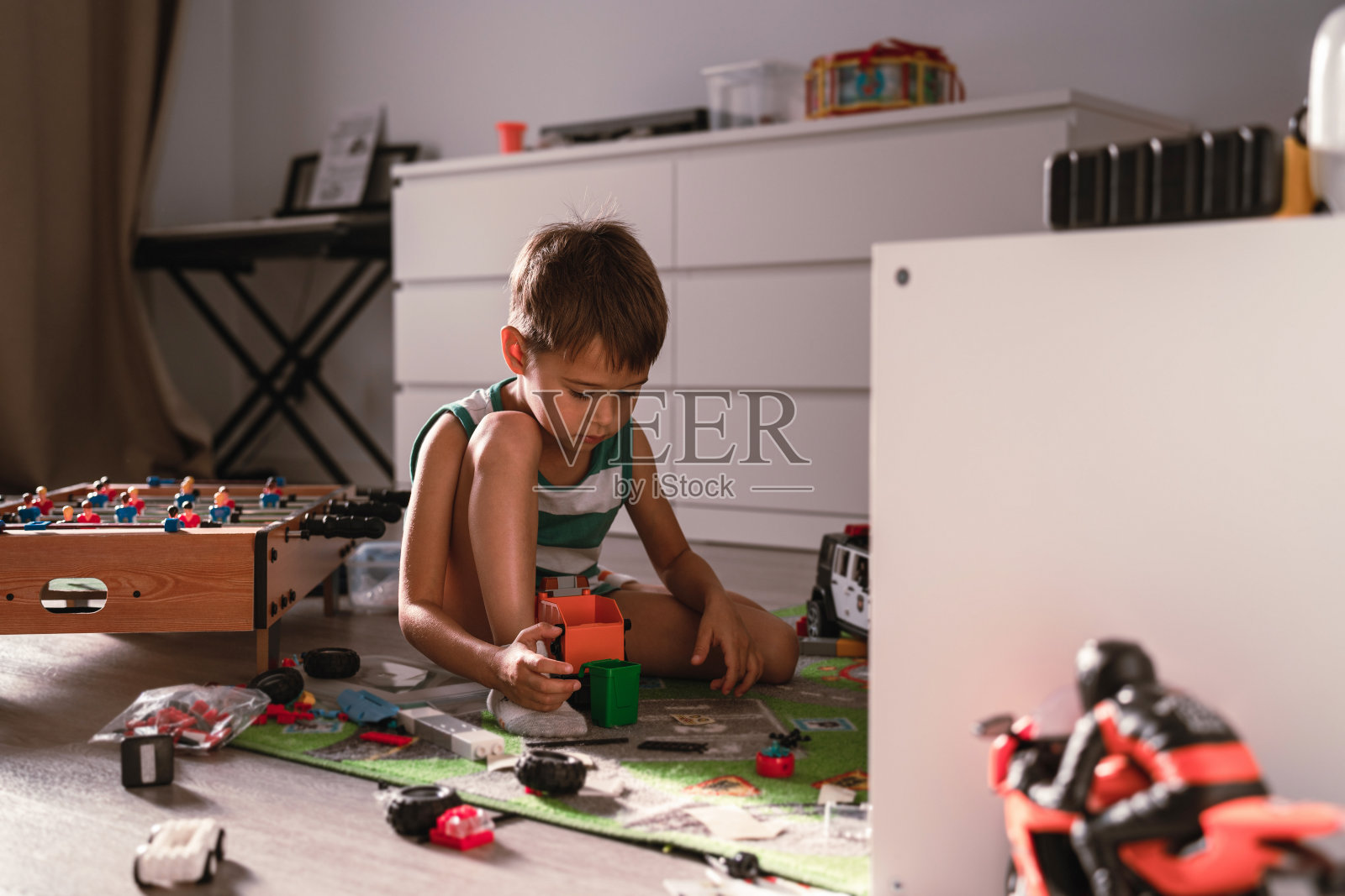 在一间阳光明媚的现代房间里，一个快乐的男孩正在玩他的玩具照片摄影图片