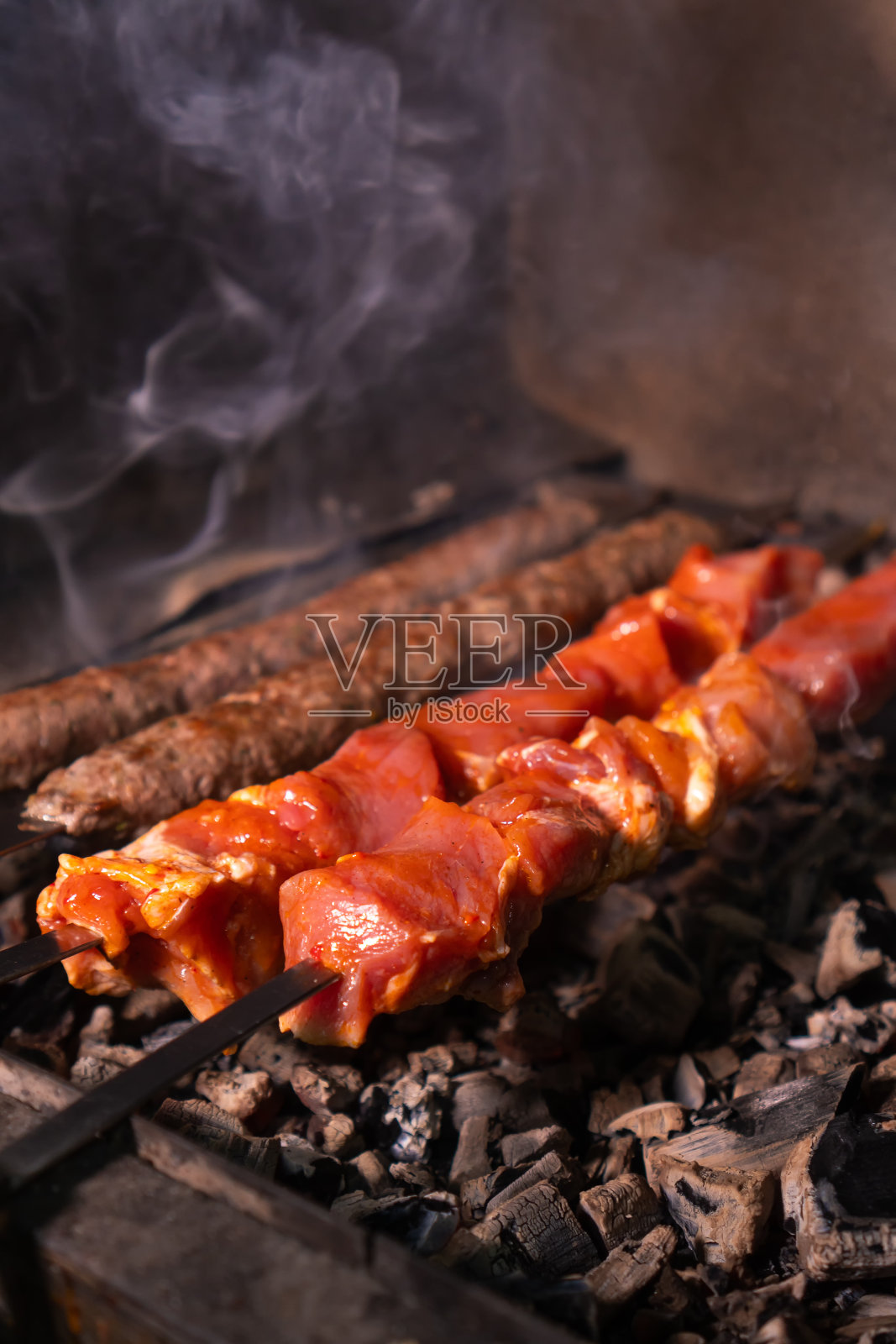 开胃烤肉串或烤肉串的特写，由鲜肉和卢拉烤肉串在木炭烤架上用烟烤熟。垂直图照片摄影图片