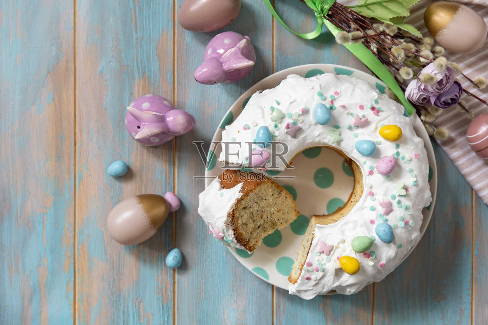 木质桌子上装饰着糖果和迷你巧克力蛋糖的复活节柠檬蛋糕。照片摄影图片