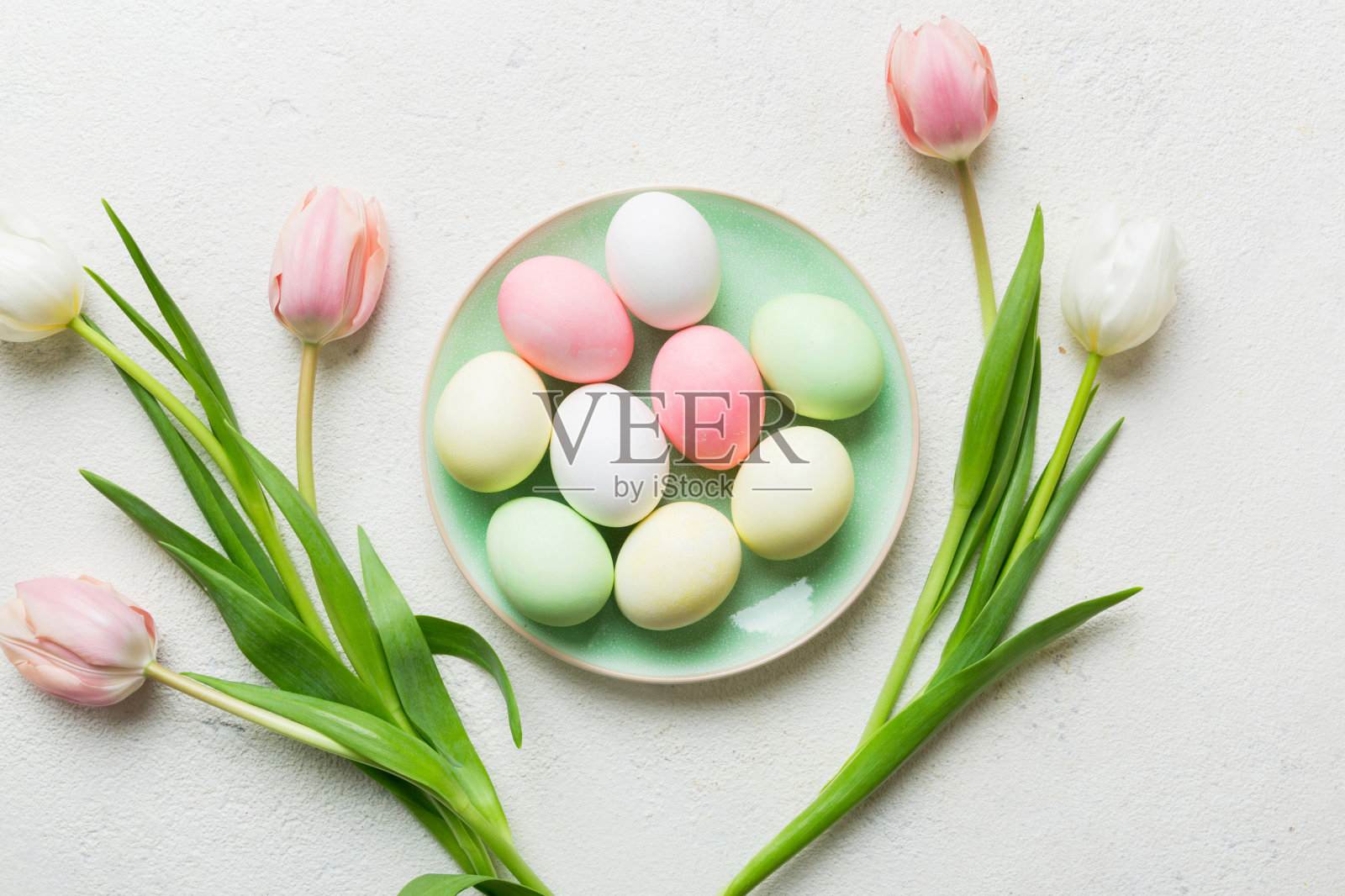复活节作文快乐。复活节彩蛋在篮子里，彩色的桌子上有黄色的郁金香。自然染色彩色鸡蛋背景顶视图与复制空间照片摄影图片