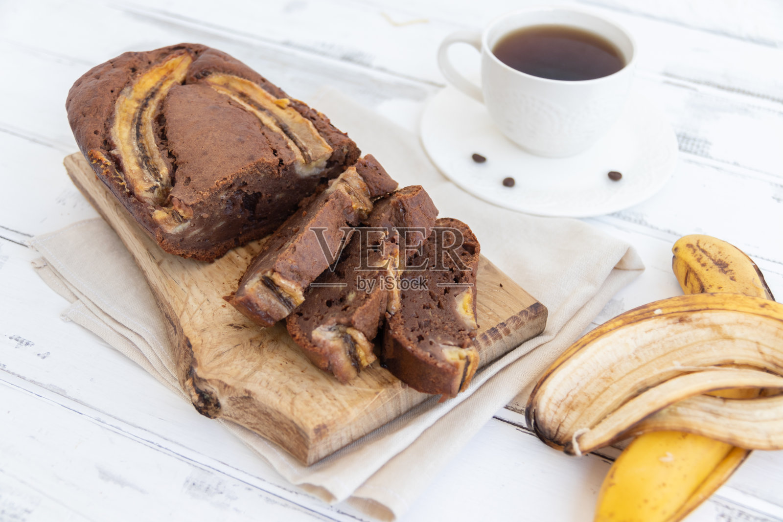 自制的香蕉面包放在白色桌子上的木板上。早餐与膳食营养的概念。照片摄影图片
