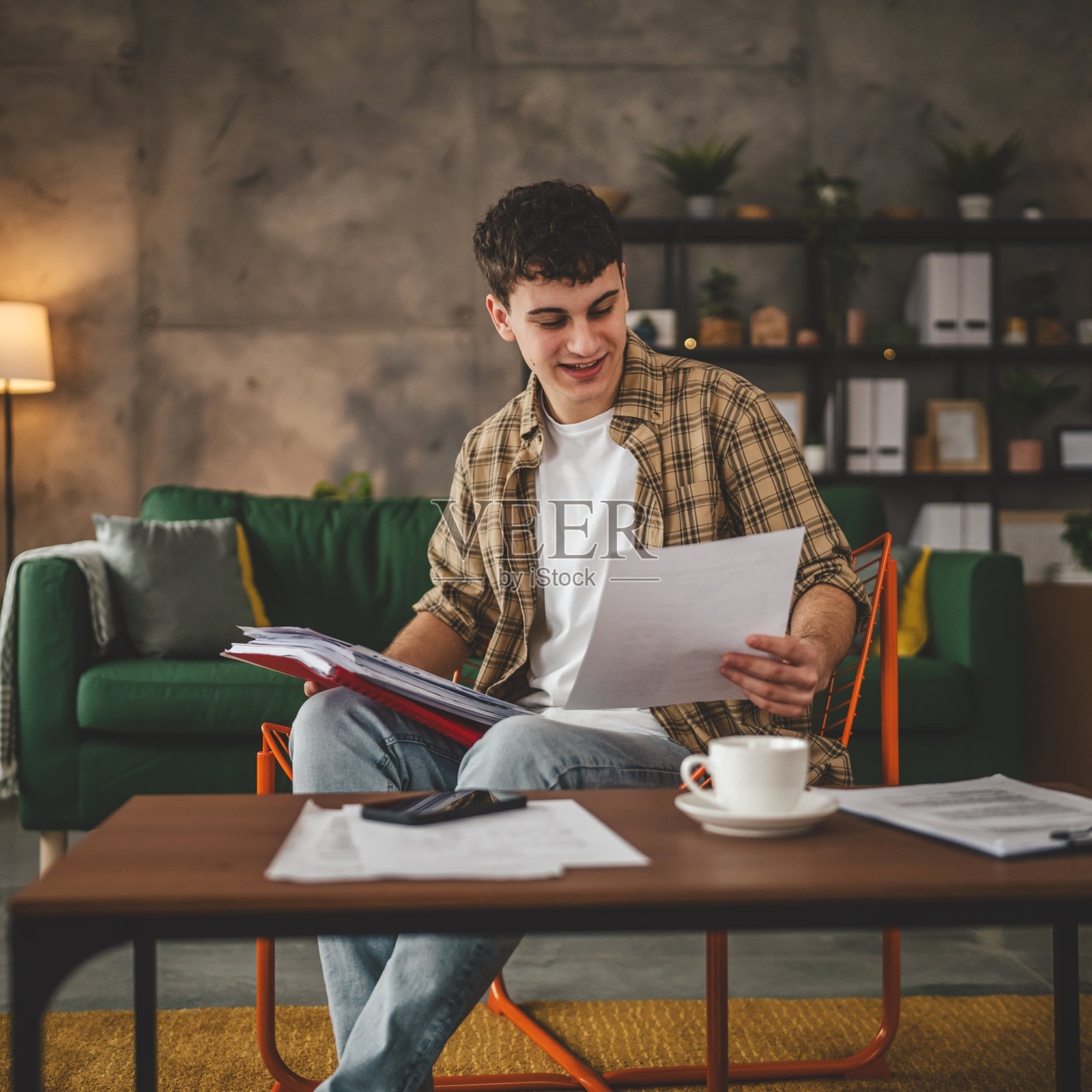 年轻人拿着纸在信里读好消息坐在家里收到信件银行对账单或通知邀请奖学金喜讯或考试报告照片摄影图片