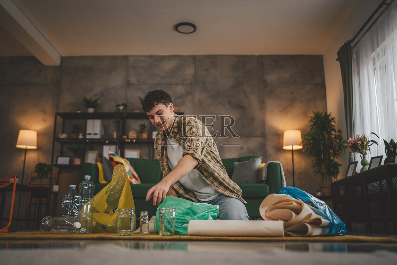 一名年轻男子在家中回收分类废旧塑料纸和玻璃照片摄影图片