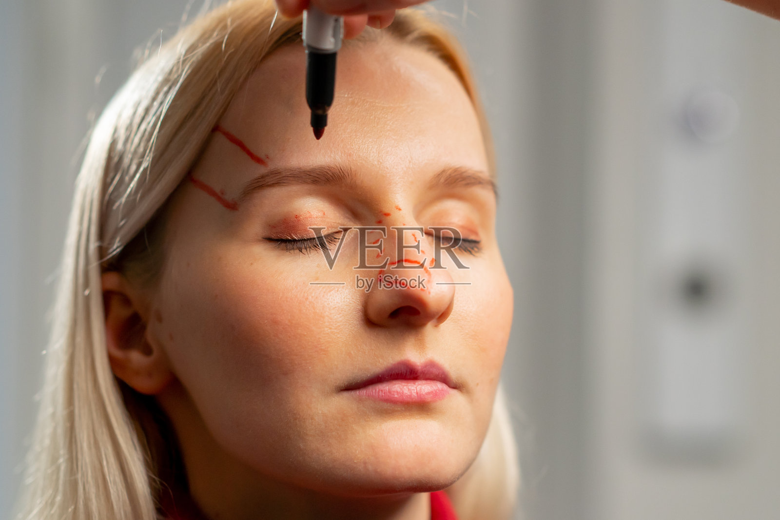 整形外科诊所里，医生在手术前在一个小女孩的脸上做标记照片摄影图片