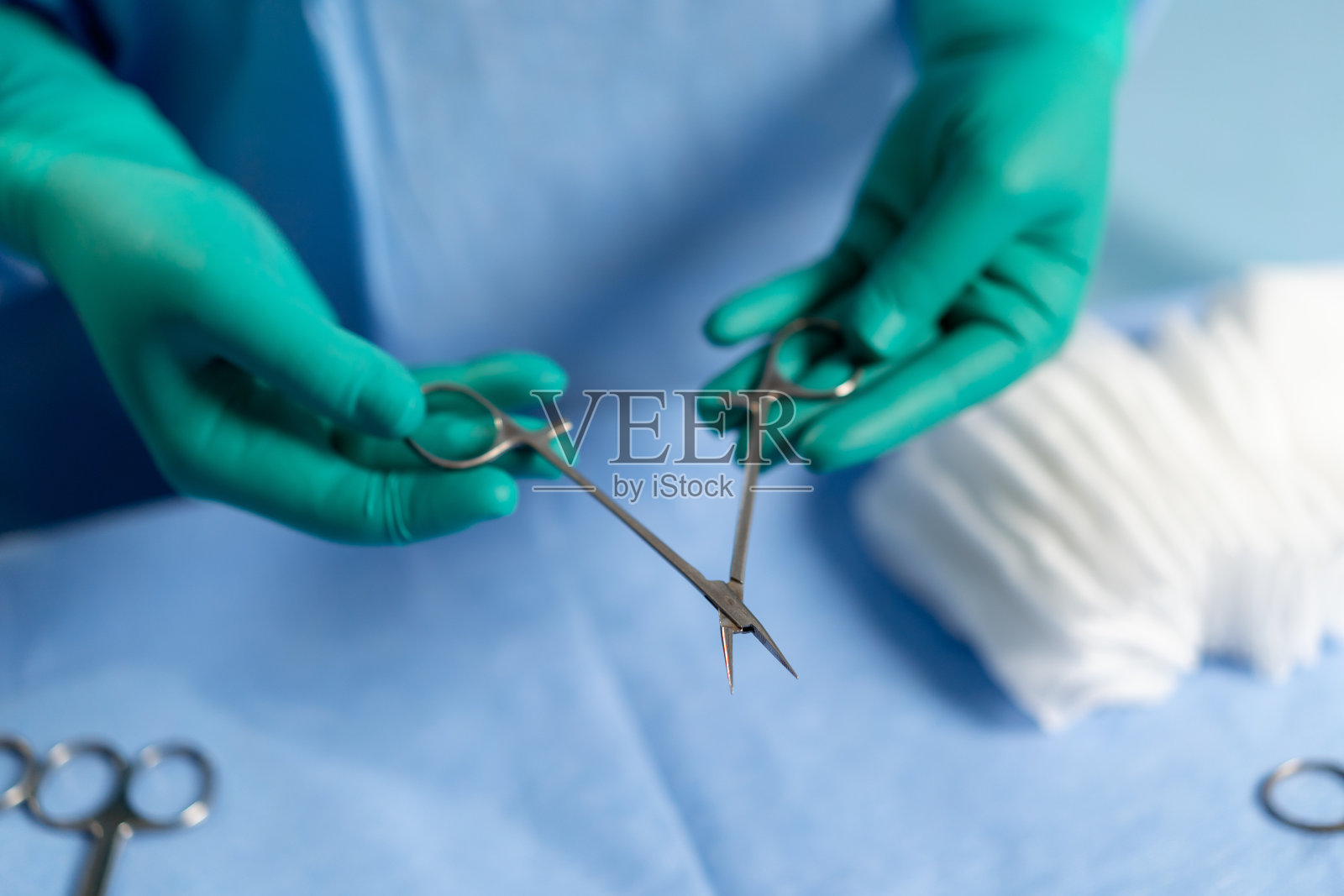 手术室里的特写镜头，一位戴着绿色手套的医生手持手术剪刀照片摄影图片