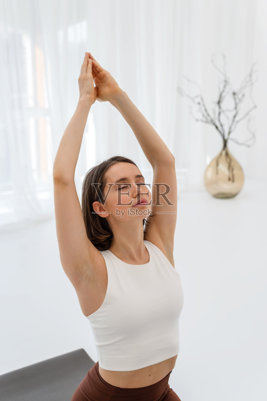 年轻女子在瑜伽练习时在垫子上做早操。体育锻炼。健康生活理念，女性健康。照片摄影图片