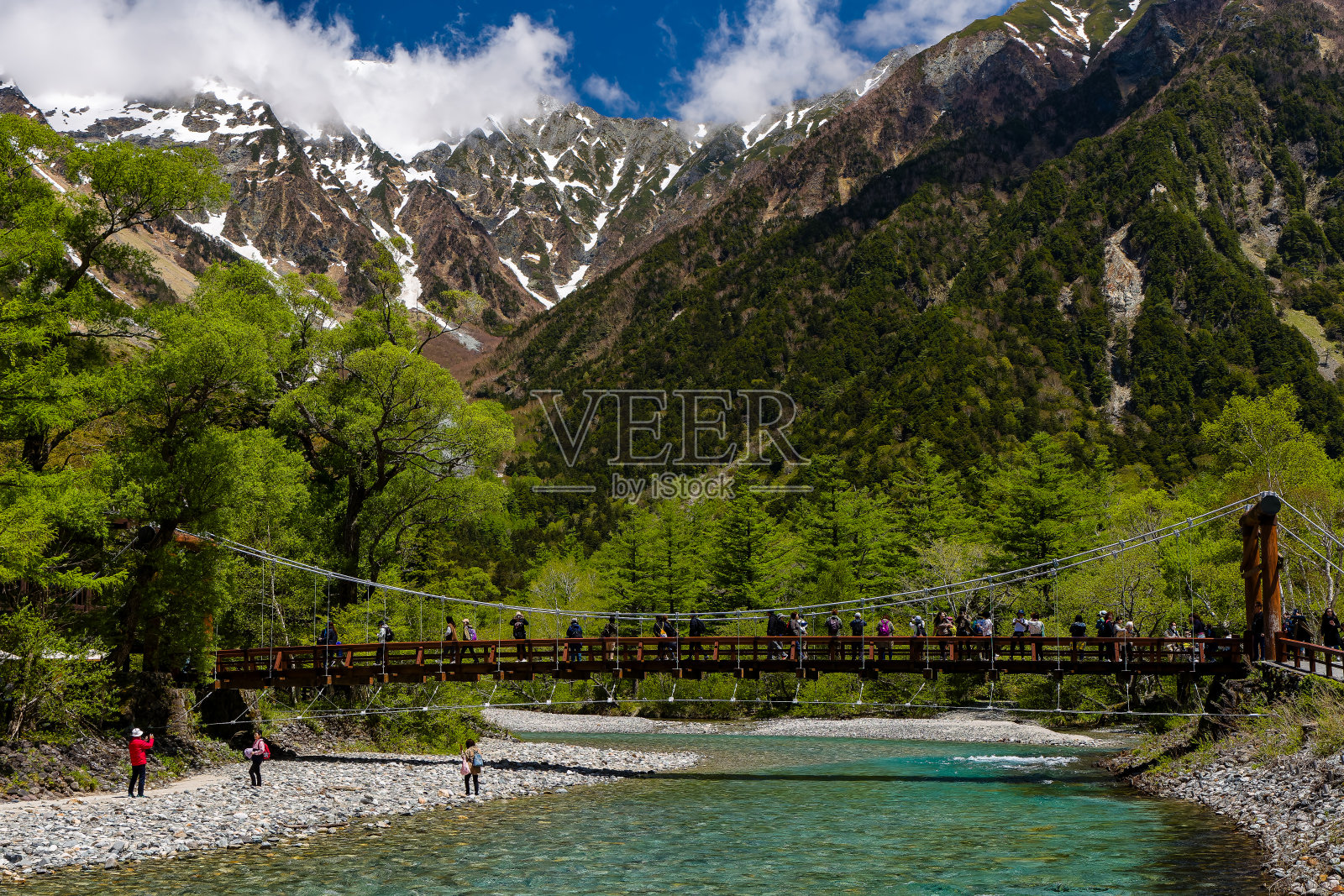 卡巴桥上的徒步旅行者和游客，身后是白雪覆盖的Kotaka山脉山峰。照片摄影图片