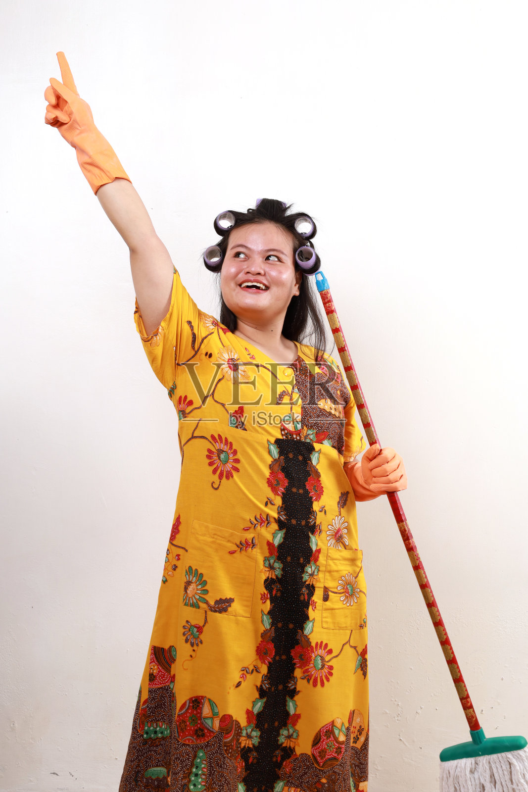 激动的亚洲女管家拿着拖把站着。孤立于白色照片摄影图片