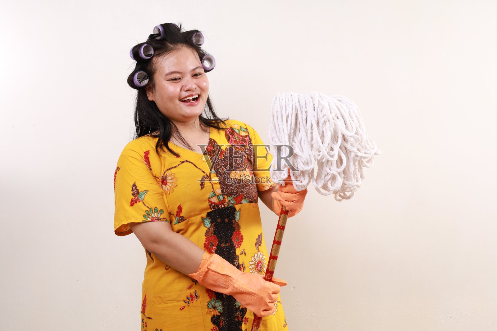 激动的亚洲女管家站在一边，手里拿着拖把，脸上带着快乐的表情照片摄影图片