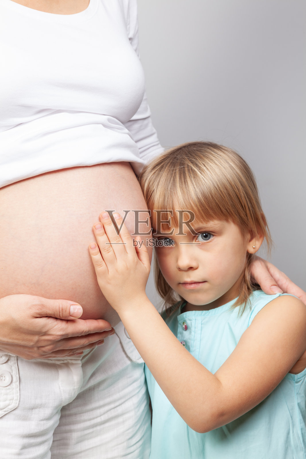 好奇的小女孩等着感受她未出生的兄弟姐妹的踢腿照片摄影图片