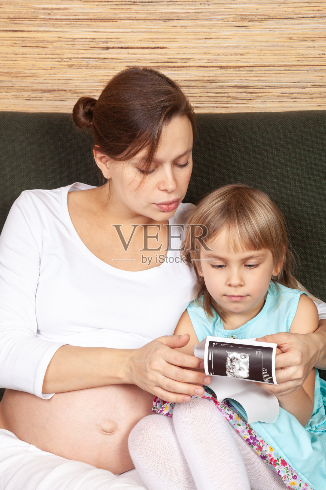 准妈妈和女儿在看超声波照片摄影图片