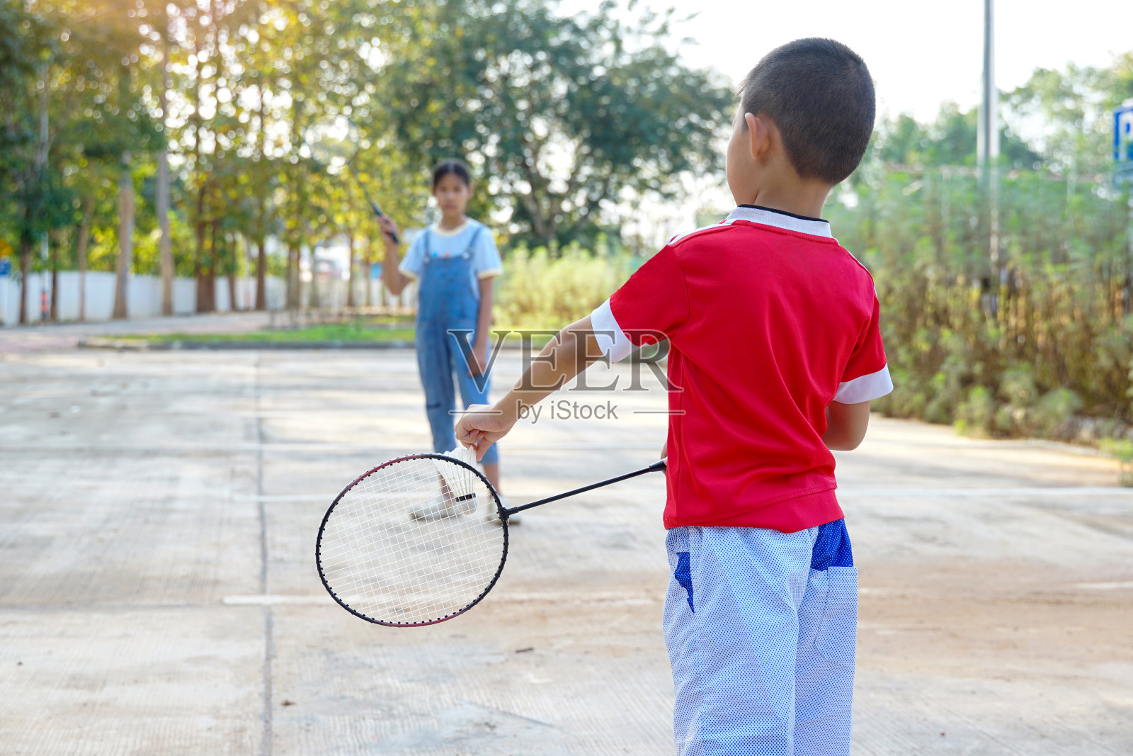 亚洲女孩和男孩在假期一起在公园户外打羽毛球。柔和和选择性聚焦。照片摄影图片