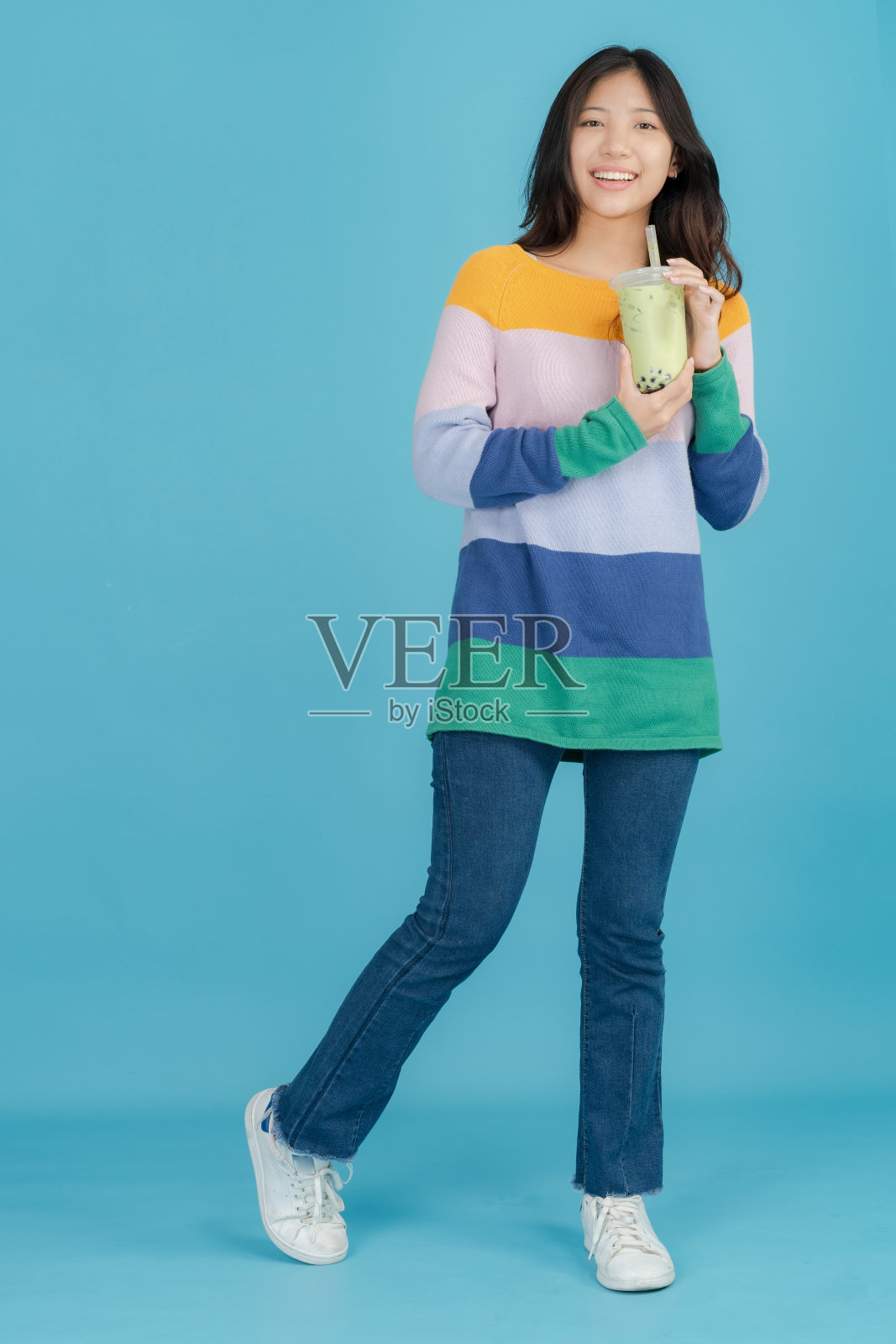 美丽的年轻女子手里拿着珍珠奶茶，开心地笑着照片摄影图片