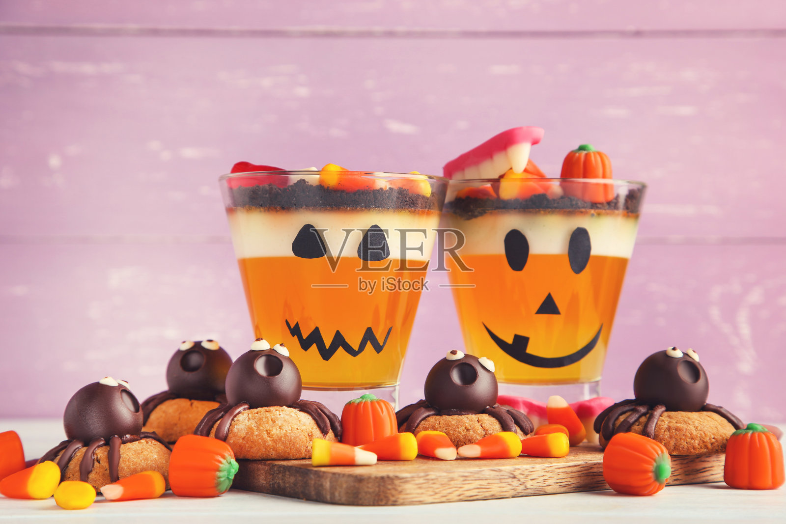 万圣节果冻玻璃杯与糖果和饼干在紫色的背景照片摄影图片