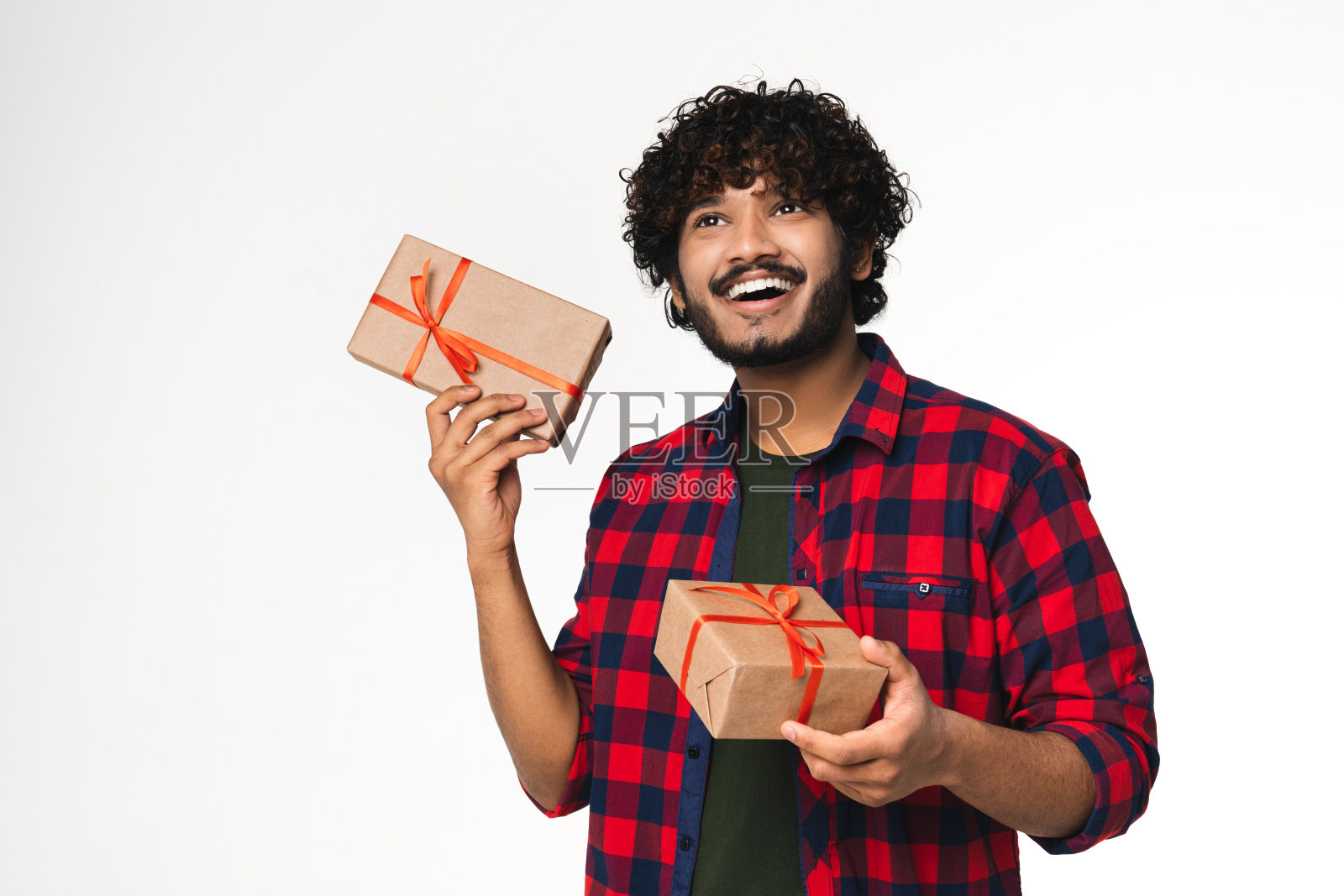 乐观的年轻印度男子摇晃着白色背景上孤立的礼物盒。照片摄影图片