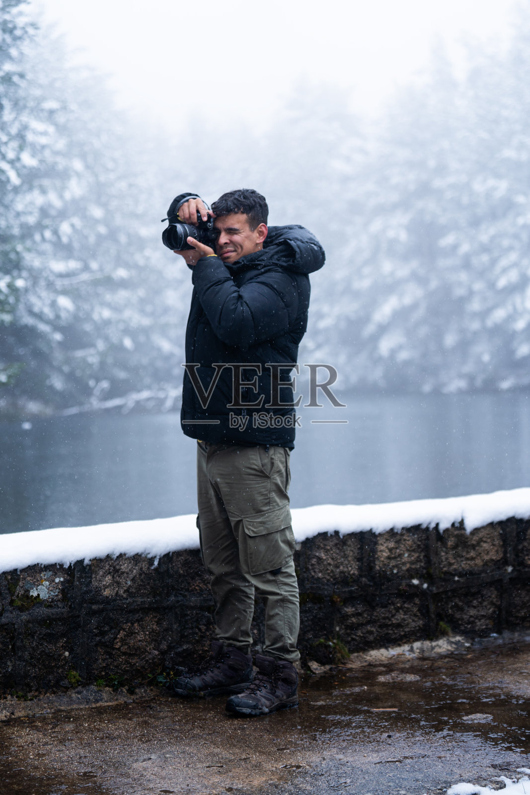 探险探索者探索瓜达拉马山脉的冬季，用相机拍摄雪景。照片摄影图片