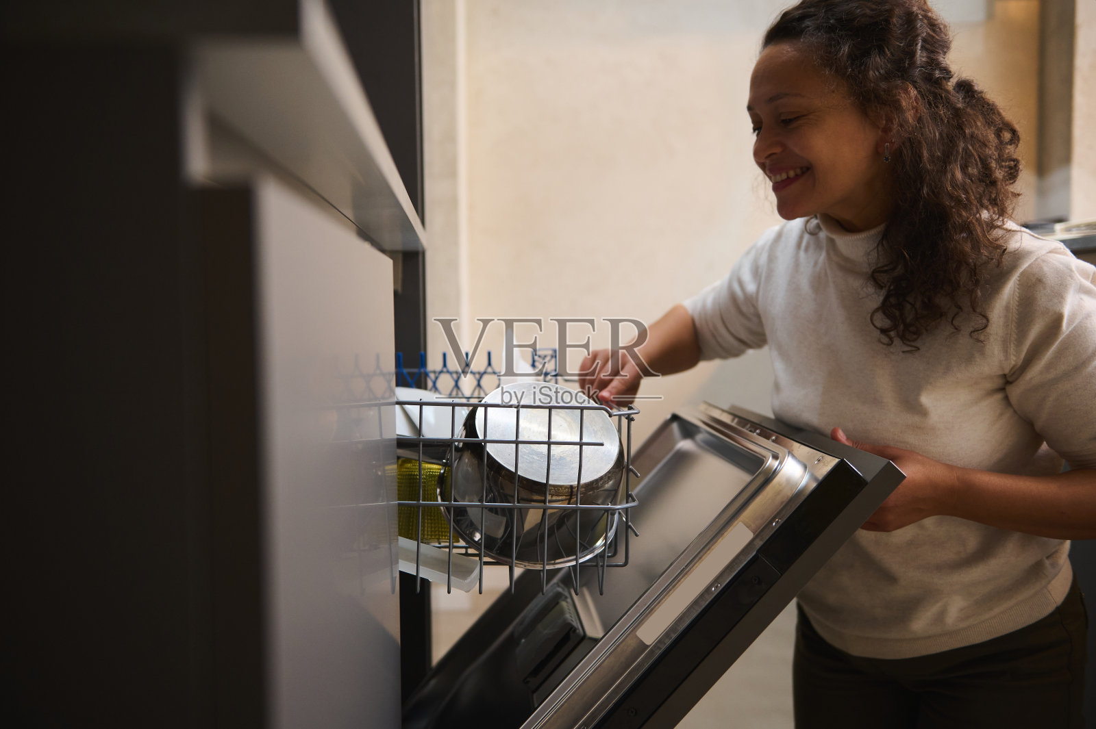 一个快乐微笑的女人在厨房里使用现代洗碗机的真实肖像。管家。家务活。人与家的生活规律照片摄影图片