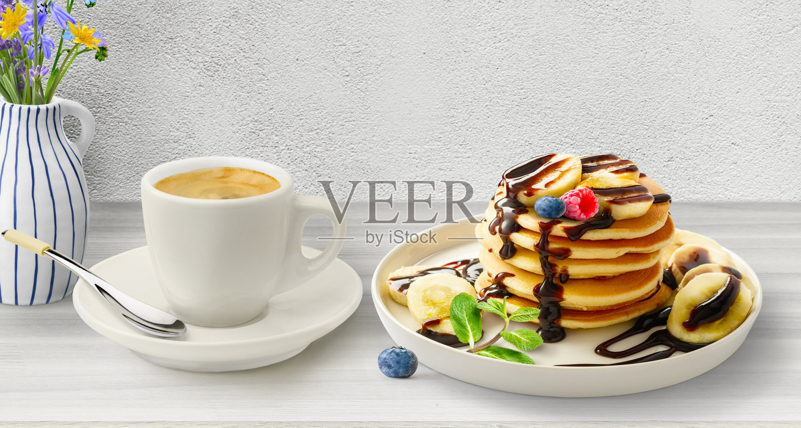 一盘巧克力酱煎饼，桌上有咖啡。早餐照片摄影图片