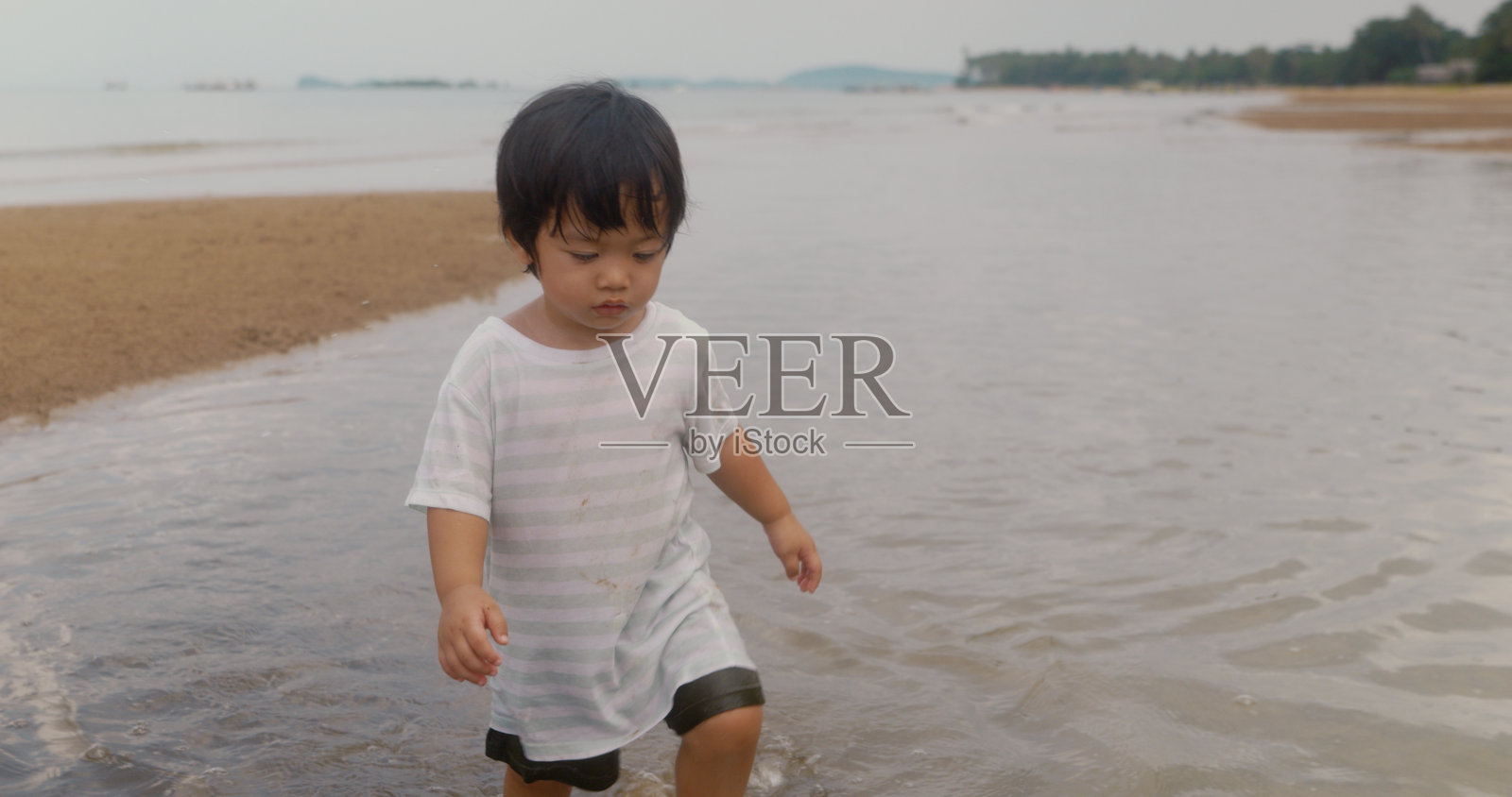 快乐的亚洲男孩喜欢海滩和大海。笑着在沙滩上奔跑。照片摄影图片