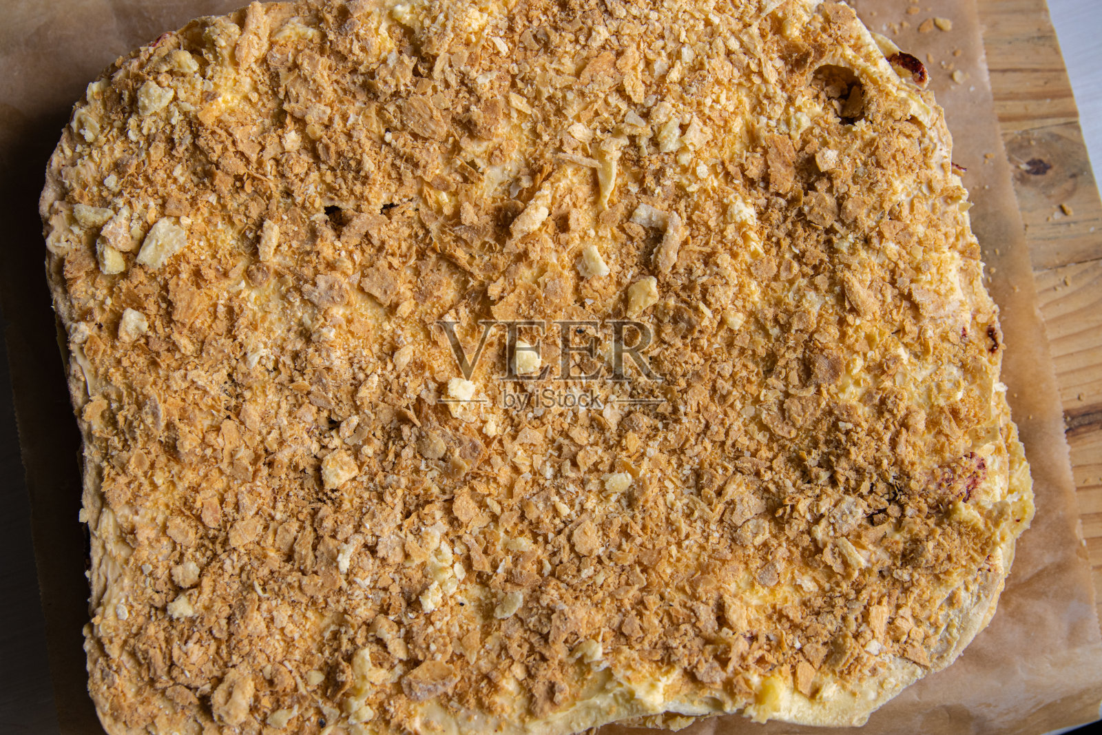 支持过程。法国拿破仑蛋糕的酥皮层特写，铺在木质砧板上的底纸上。法式奶油奶油酥皮。前视图。有选择性的重点。照片摄影图片