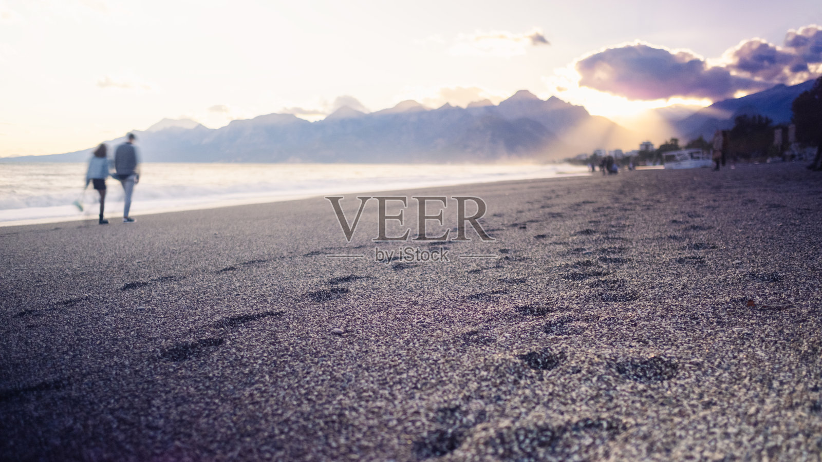 日落时分，人们在海滩上散步照片摄影图片