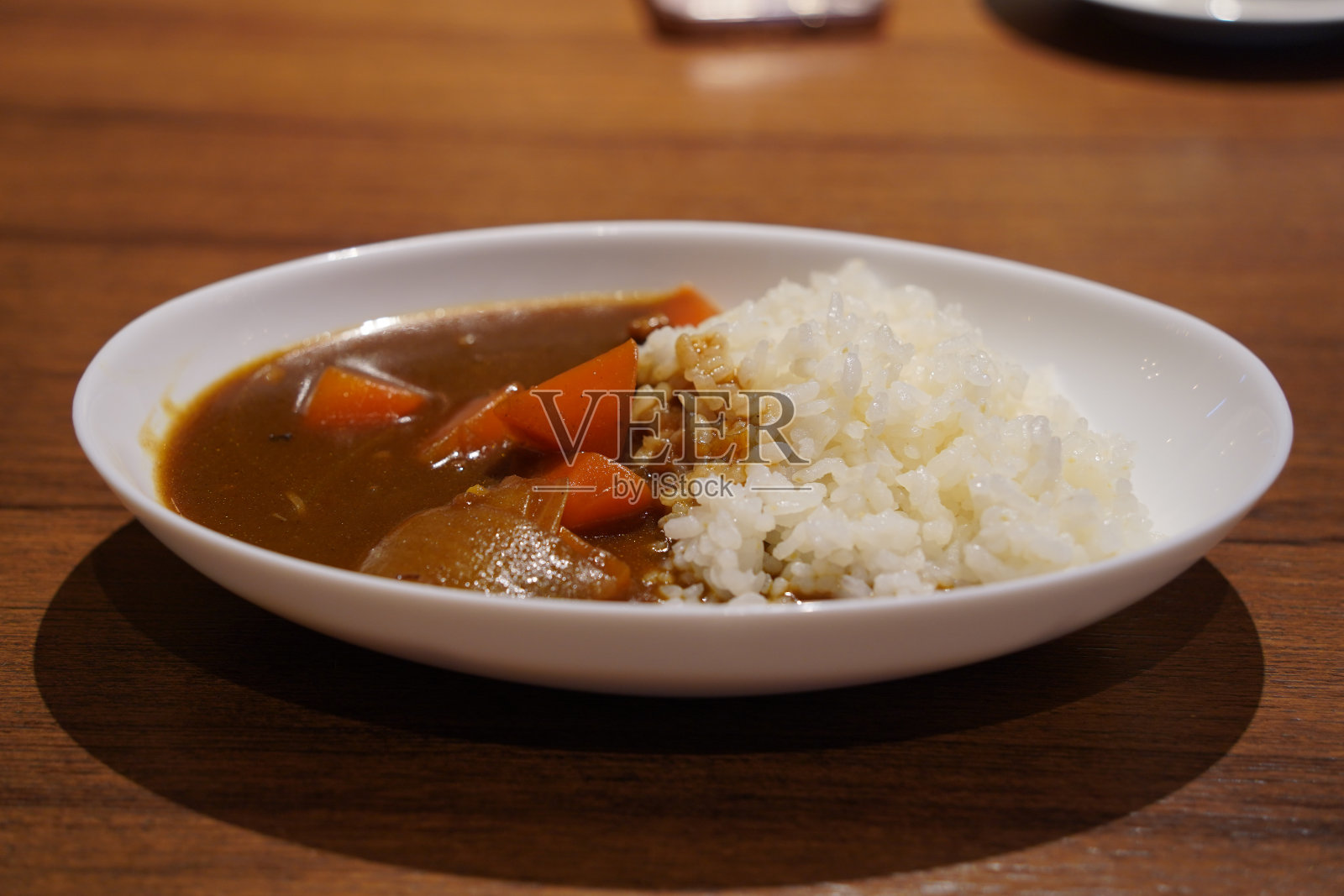 木桌上的白色盘子里放着日本咖喱饭照片摄影图片