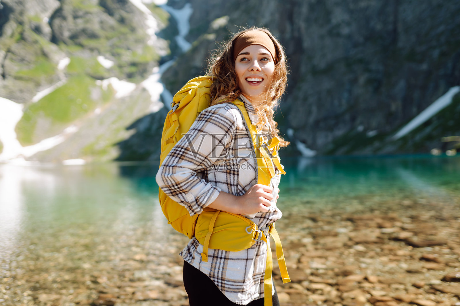 一名年轻女子背着黄色的徒步背包，在森林和悬崖之间的山间徒步旅行。照片摄影图片