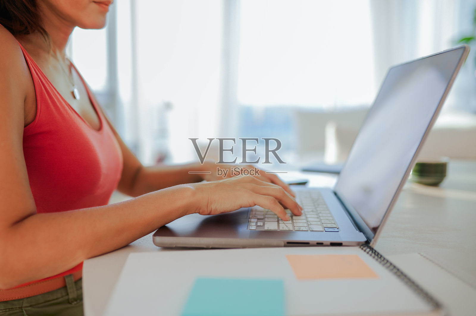 在办公桌上用笔记本电脑打字的休闲装扮女人照片摄影图片