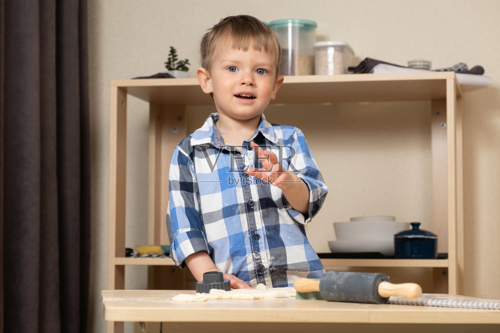 一个两岁的男孩在厨房做饭，揉面团。烹饪和孩子照片摄影图片