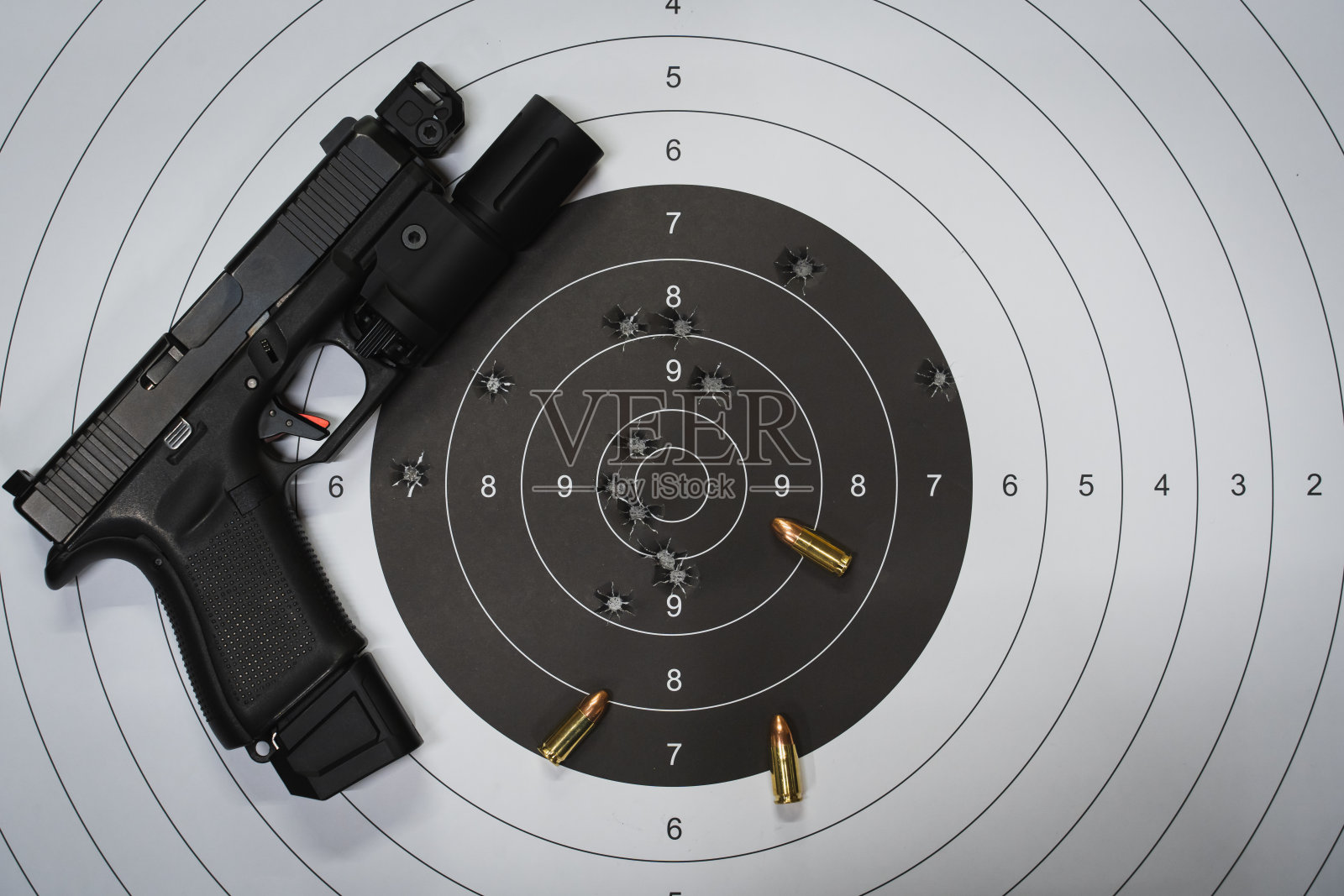战术手枪和中间有弹孔的纸靶。照片摄影图片