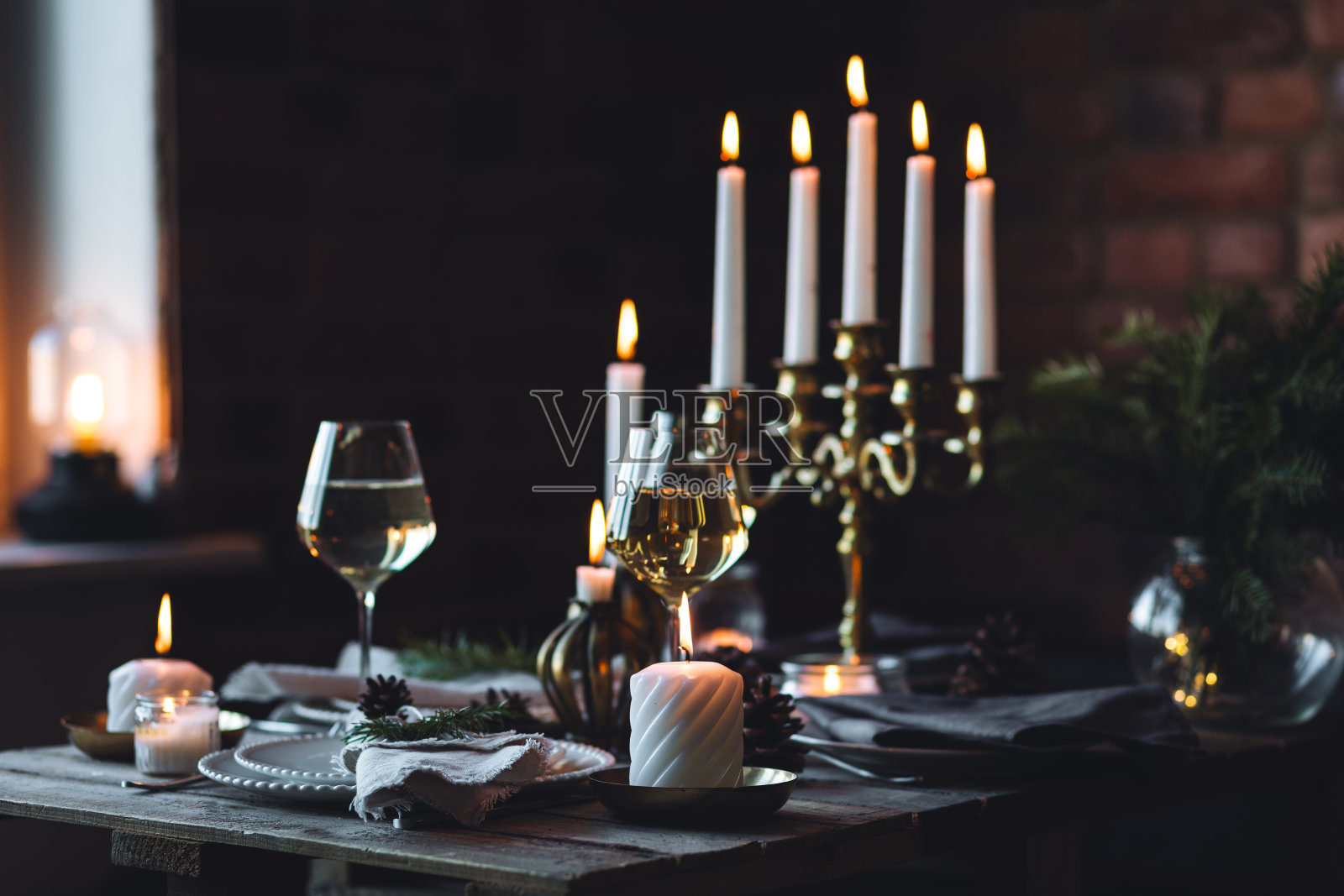 圣诞家庭晚餐质朴优雅的餐桌装饰。中间饰有白色蜡烛、松果、冷杉树枝。零废弃物环保家装。温馨的氛围，木质背景。照片摄影图片