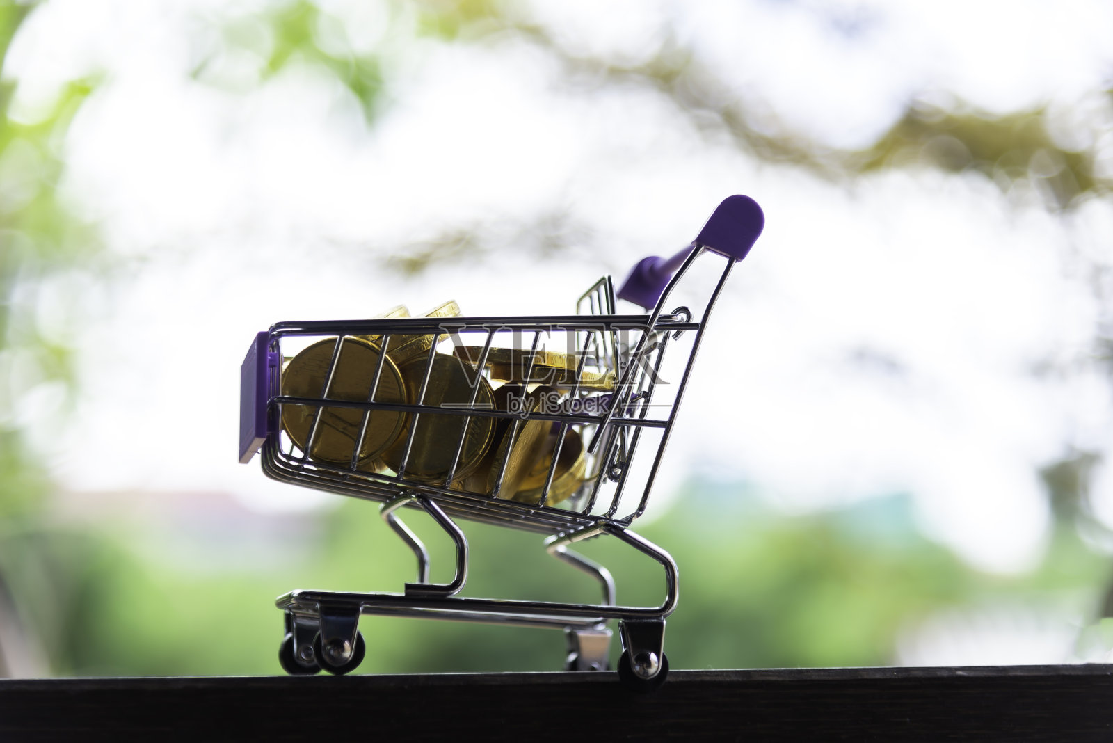 购物车里装满金币的木制桌子上的电子商务在绿色的网上市场背景下取得了成功。照片摄影图片