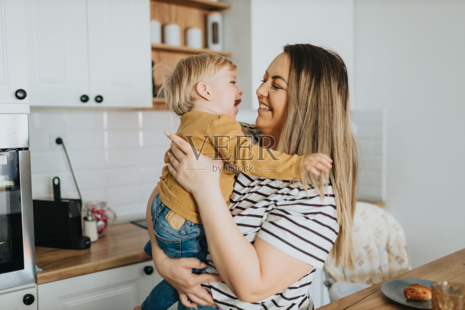 妈妈抱着可爱的小男孩在家里笑照片摄影图片