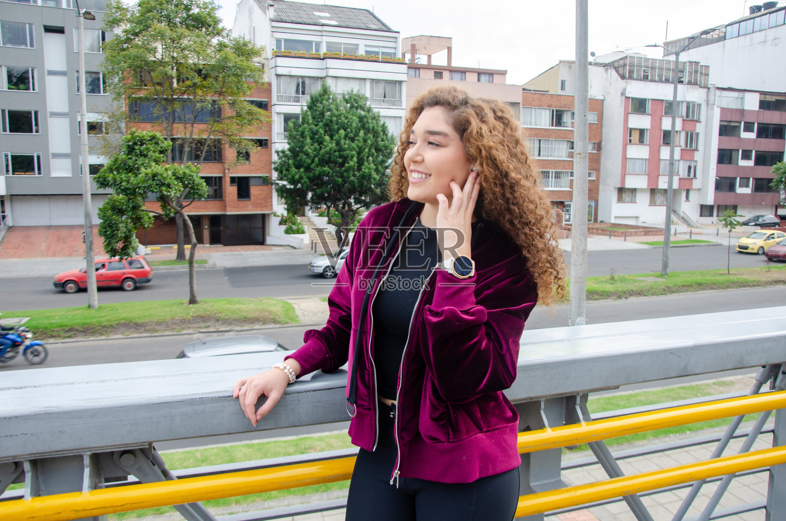 一个快乐自信的漂亮卷发女人的特写，她在人行天桥上戴着无线耳机听音乐照片摄影图片