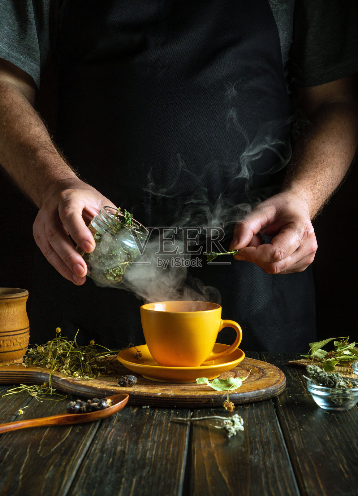 一名男子用草药泡茶。家庭治疗流感病毒或感冒的传统医学概念。在马克杯中加入干薄荷照片摄影图片