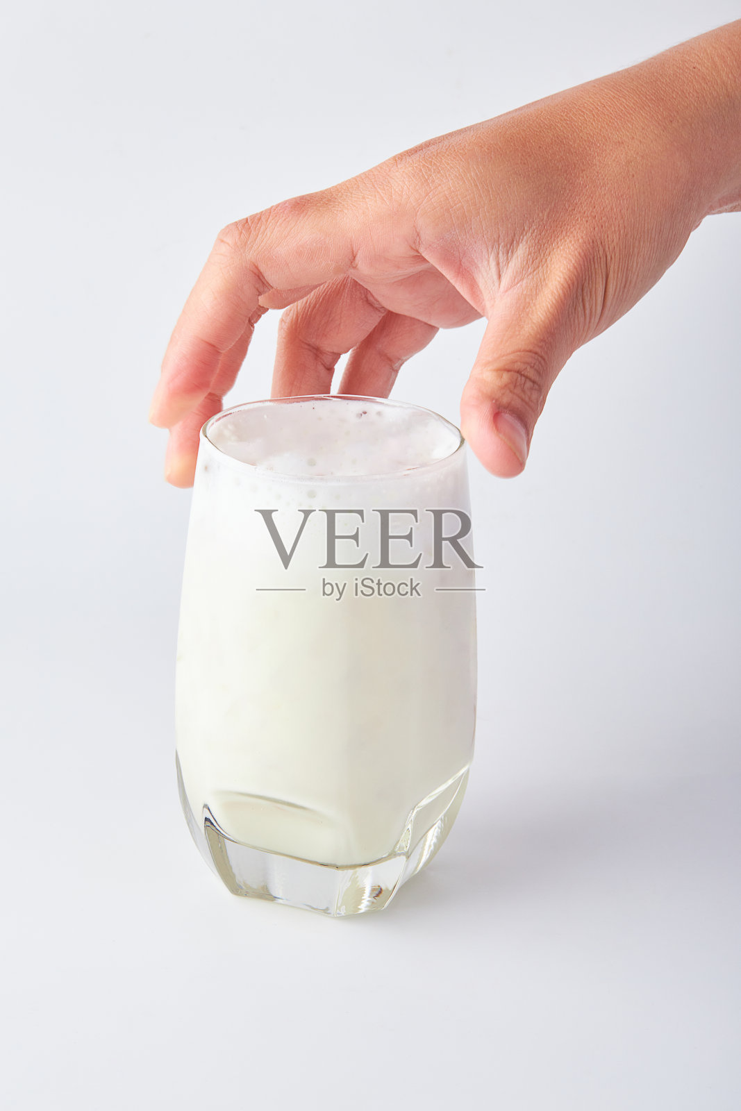 手正要拿起那杯孤立在白色背景上的鲜奶。照片摄影图片